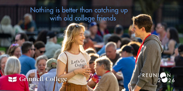 2 alums talking with backdrop of people seated for a meal