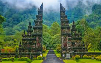 The split stone gate in Bali on the Handara Golf and Resort. The stone gate is set on a backdrop of green trees of various shades.