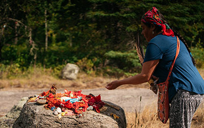 First Nations person participating in a ceremony and leaving offerings in Whiteshell Provincial Park, Manitoba.