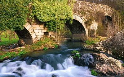 he Medieval Bridge Puente San Xoan across the River Furelos, outside the Town of Melide in Galicia, on the Way of St James Camino de Santiago.