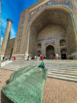 A woman walks into a stone building while wearing a flowing green silk robe.