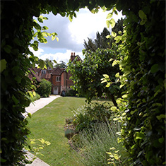 Jane Austen&rsquo;s Museum and House taken through an opening in a green hedge.