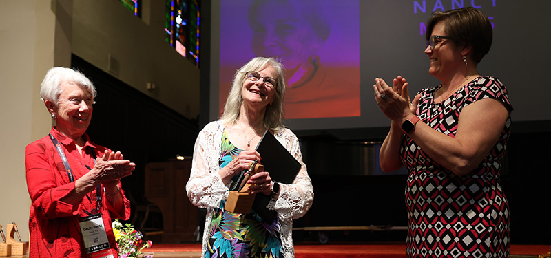Becky Reetz Neal &rsquo;65, left, and Kate Goddard &rsquo;91 lead the applause for Nancy Mills &rsquo;72 