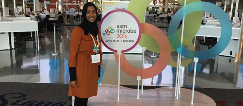 Zina Ibrahim ’17 poses with welcome signs to the 2016 American Society for Microbiology Microbe Conference in Boston.