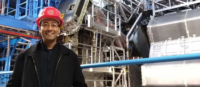 Suyog Shrestha ’06 poses in front of the CERN Large Hadron Collider.
