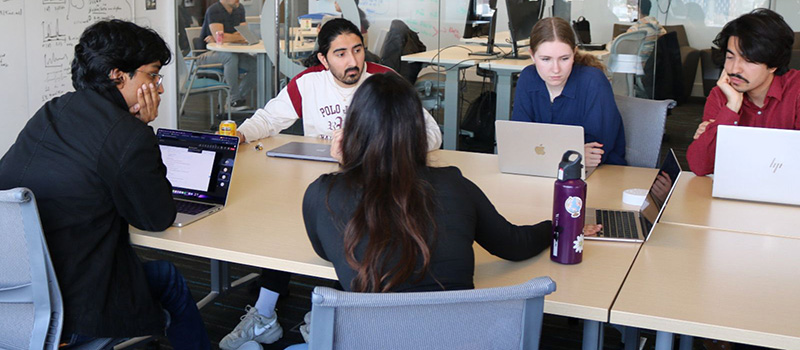 Alexa Hatcher ’27 and Akram Safiyazov ’28 join Anshul Tambay ’20 in a meeting with his co-workers.