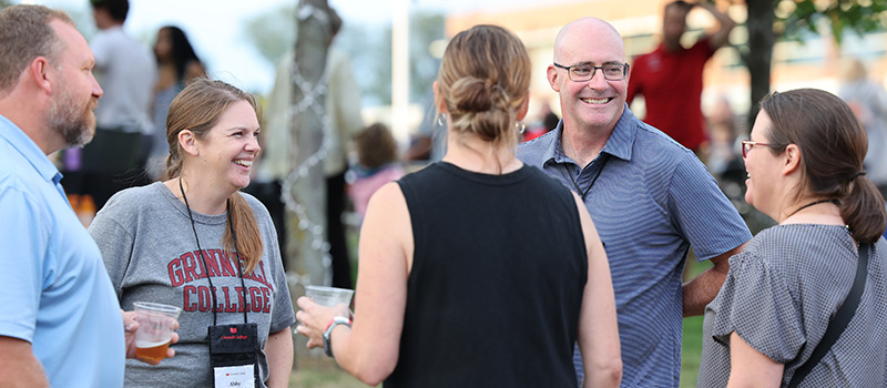 Football alumnus Evan Petig ’98 and his wife, Abby Copeman Petig ’01, visit with Grinnellians during the outdoor celebration Saturday evening.