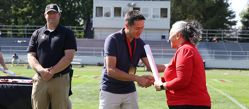 Felipe Bautista ’02 shakes hands with Director of Athletics Holly Roepke.