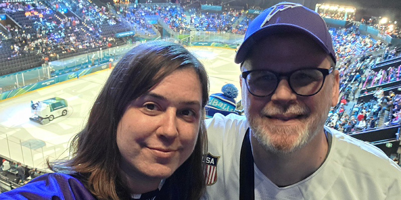 Dinah Zebot &rsquo;03 and Joe Ambroson &rsquo;00 take a selfie with an ice hockey rink in the background.