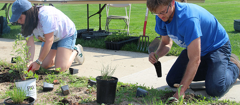 Two student plant native prairie plantings on campus. 