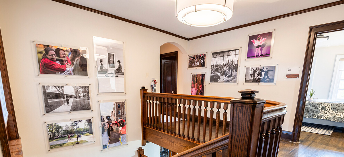 Several photos of past alumni and events line the walls of the upper hallway of the Hannah Alumni House.