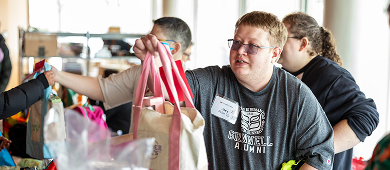 Alex Price &rsquo;15 hands a student a care packages.
