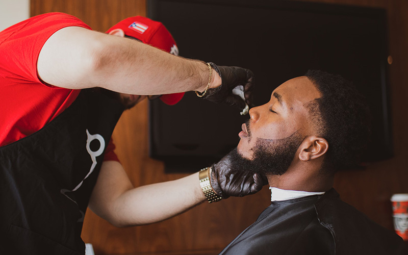 A barber cleans up the lines on his client. 