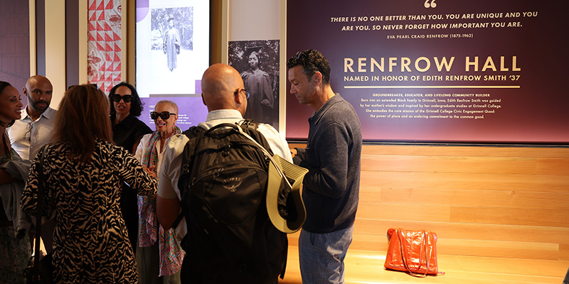 A group of Dedication attendees chat in front of a display honoring Edith Renfrow Smith.