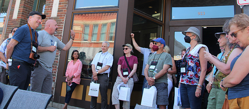 Dick Knapp ’76, left, stands next to Craig Cooper, owner of Bikes to You, as they talk about downtown Grinnell businesses during the a walking tour Friday.
