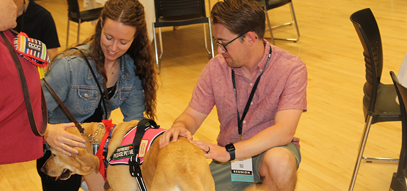 Jordan Schellinger ’15, left, and Ross Voelker, pet a dog.