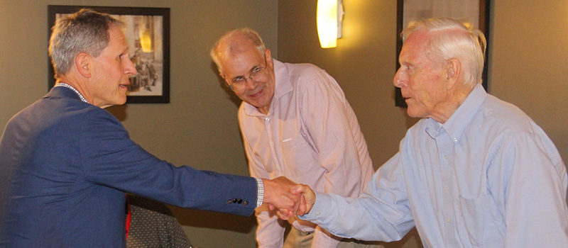 Peter Levy '80 shakes Moyer’s hand at a dinner for the professor held by the classes of 1978-1980 during Reunion 2024.