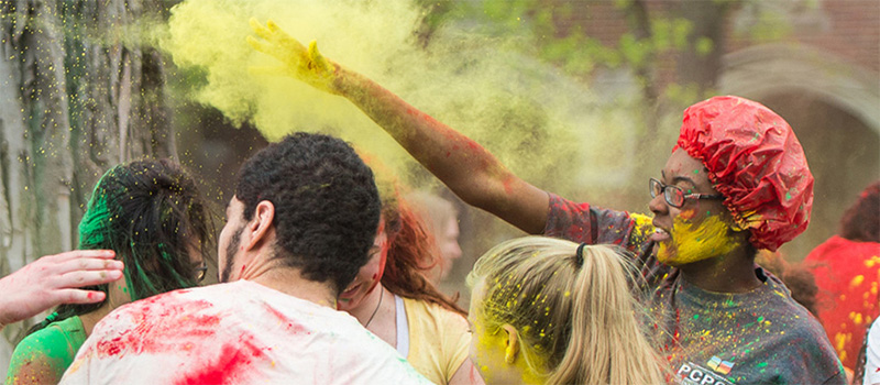 A student throws yellow color powder during a color party event.