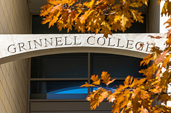Fall leaves in the foreground highlight a stone Grinnell College sign.