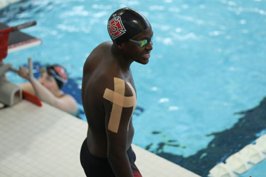 John Kafumbe ’28 in a swim cap and goggles on this side of a competition swimming pool.
