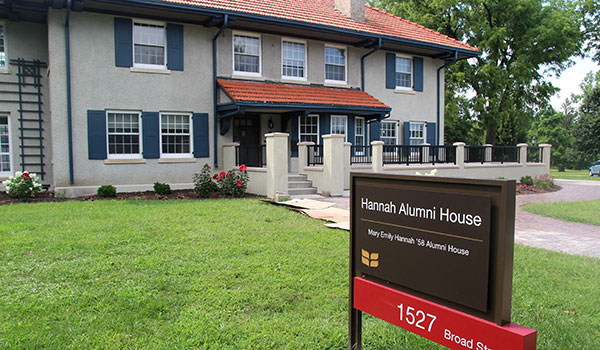 Exterior of the Hannah Alumni House. In the foreground, the campus sign for the Alumni House.