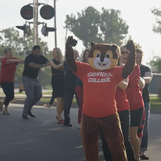 Scarlet the Squirrel and their campus friends create a congo line. 