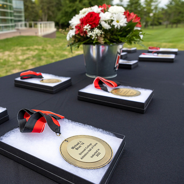 Grinnell College Athletics Hall of Fame metals displayed on a table with flowers.