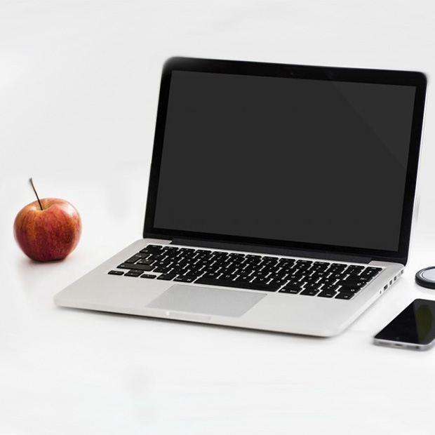 A laptop sitting next to a red apple. 