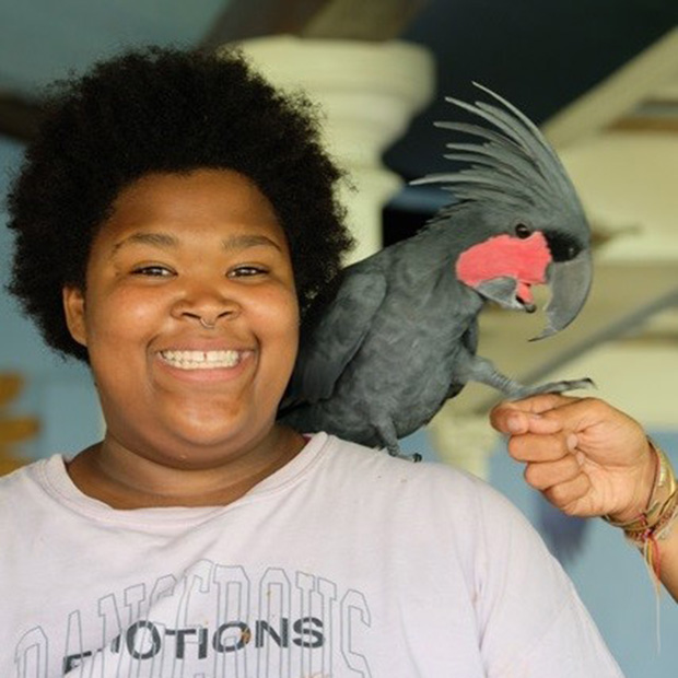 Destany Best '25 with a tropical bird on her shoulder.