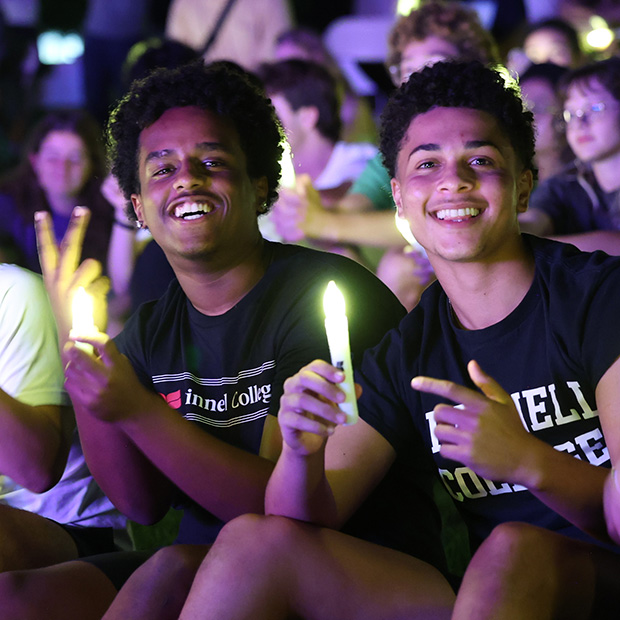 Two student pose with their glow devices during the Illumination Ceremony 2026.