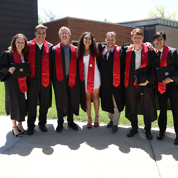 A group of student pose in commencement robes at Grinnell College.